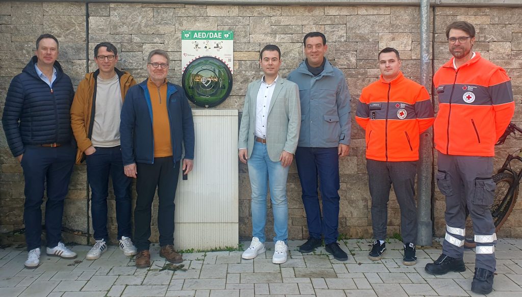 Verantwortliche der Stadt und des DRK vor dem AED am Bahnhof